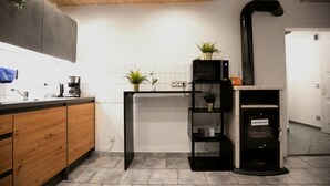 Une cuisine moderne avec des meubles en bois, un plan de travail noir, un four à micro-ondes et une petite étagère avec des plantes.