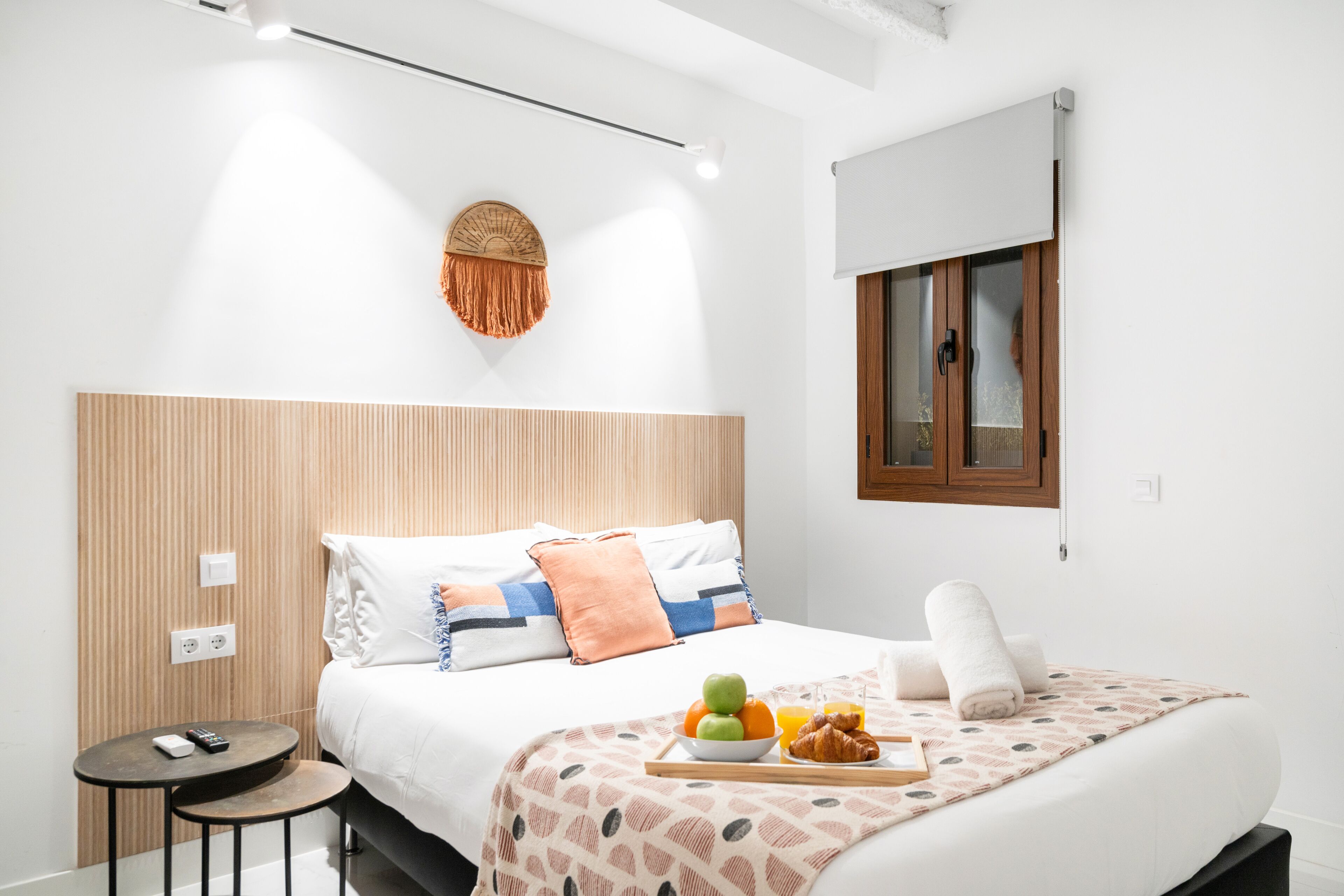 A modern hotel room with a large bed, a small table, and a wall-mounted light fixture.