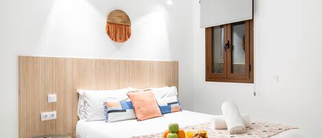 A modern hotel room with a large bed, a small table, and a wall-mounted light fixture.