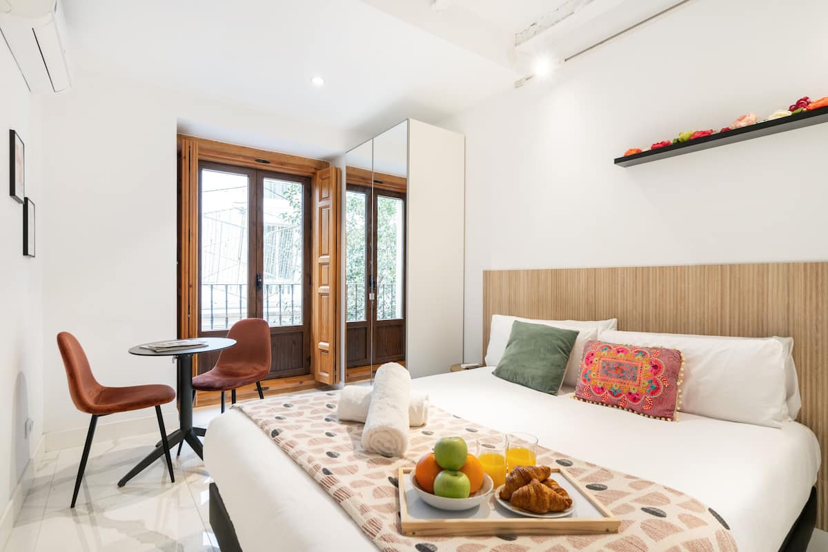 A modern hotel room with a bed, breakfast tray, and a small table with chairs.
