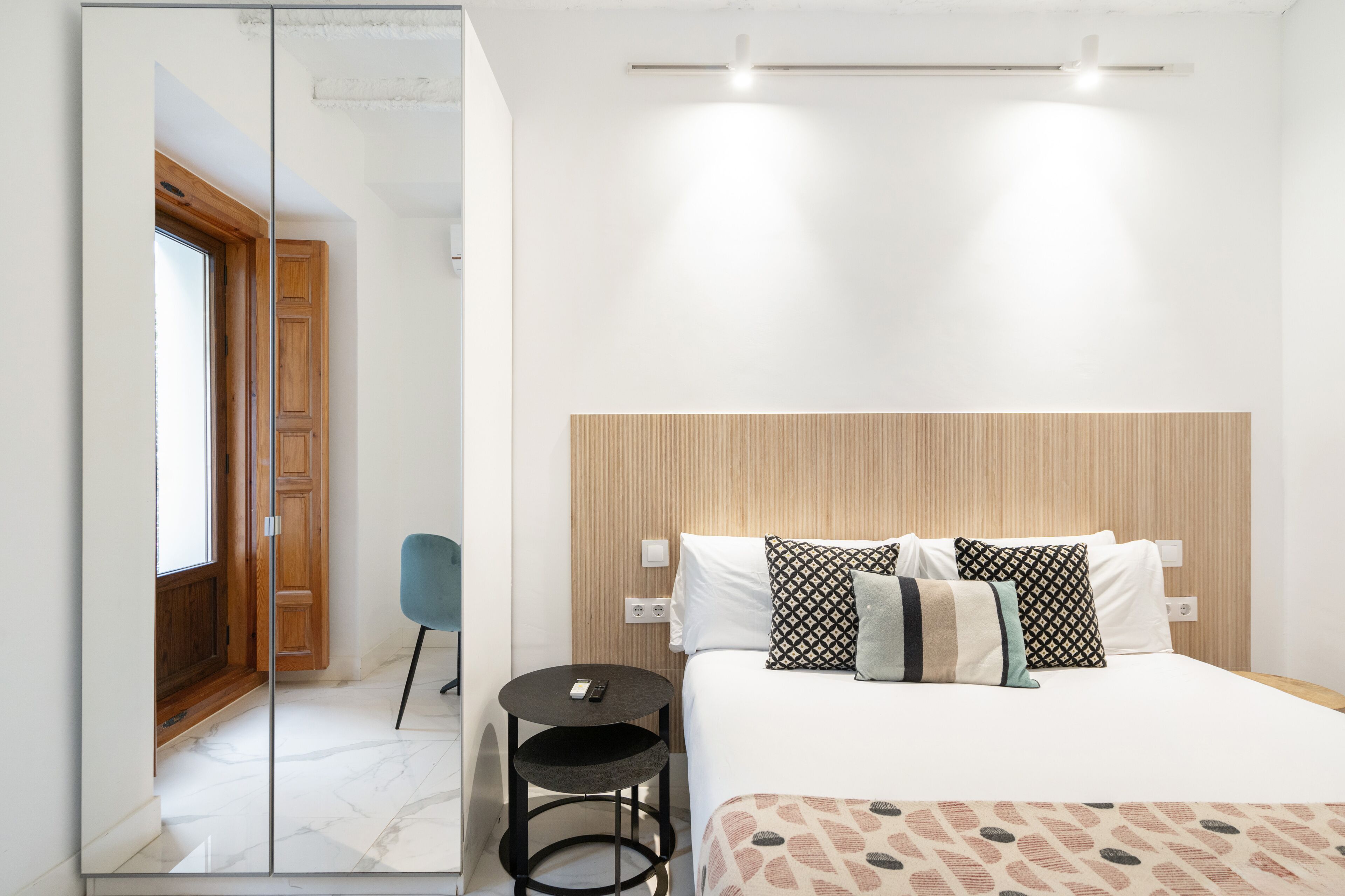 A hotel room with a bed, bedside table, and a chair.