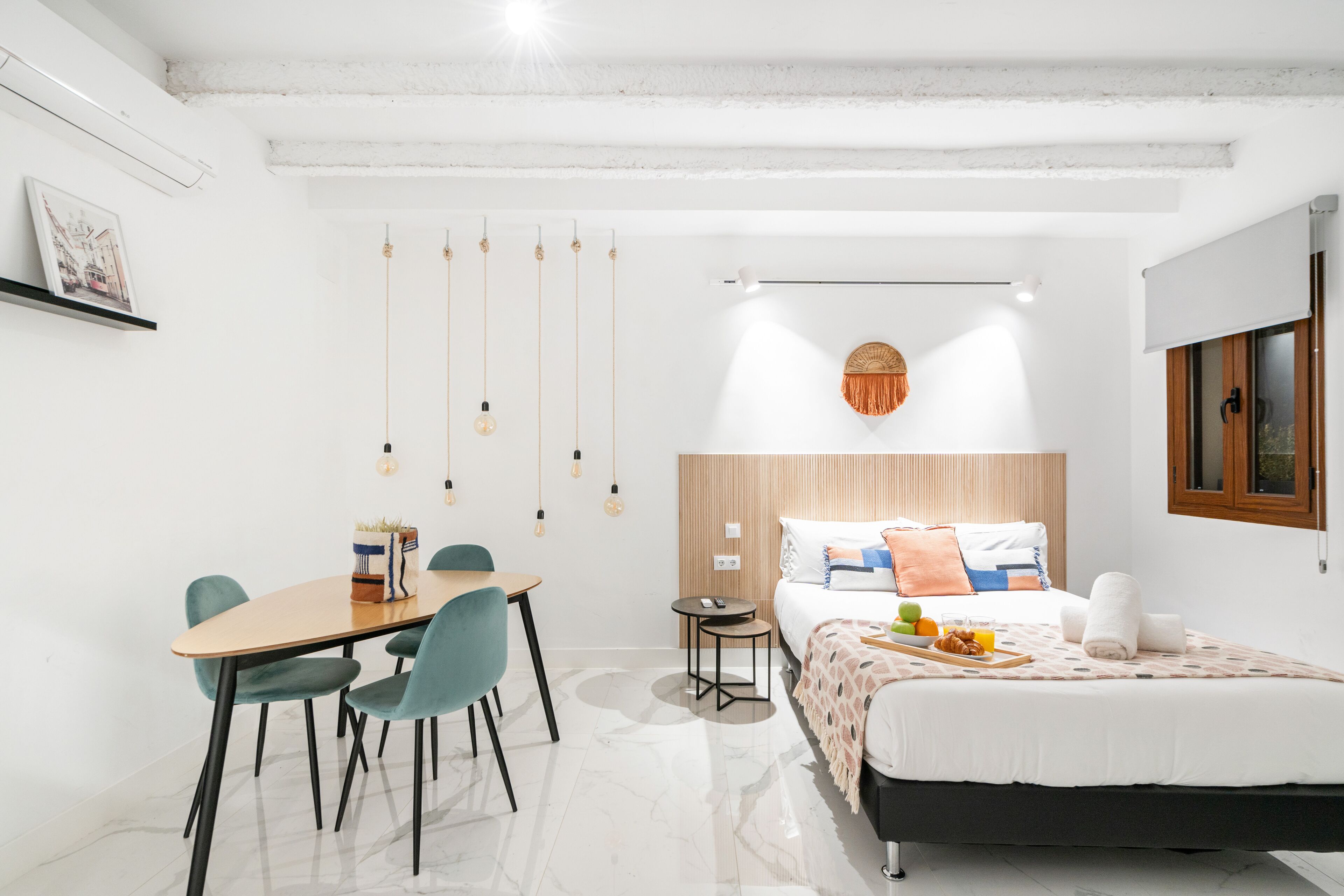 Een moderne slaapkamer met een bed, nachtkastje en een klein bureau met stoelen.