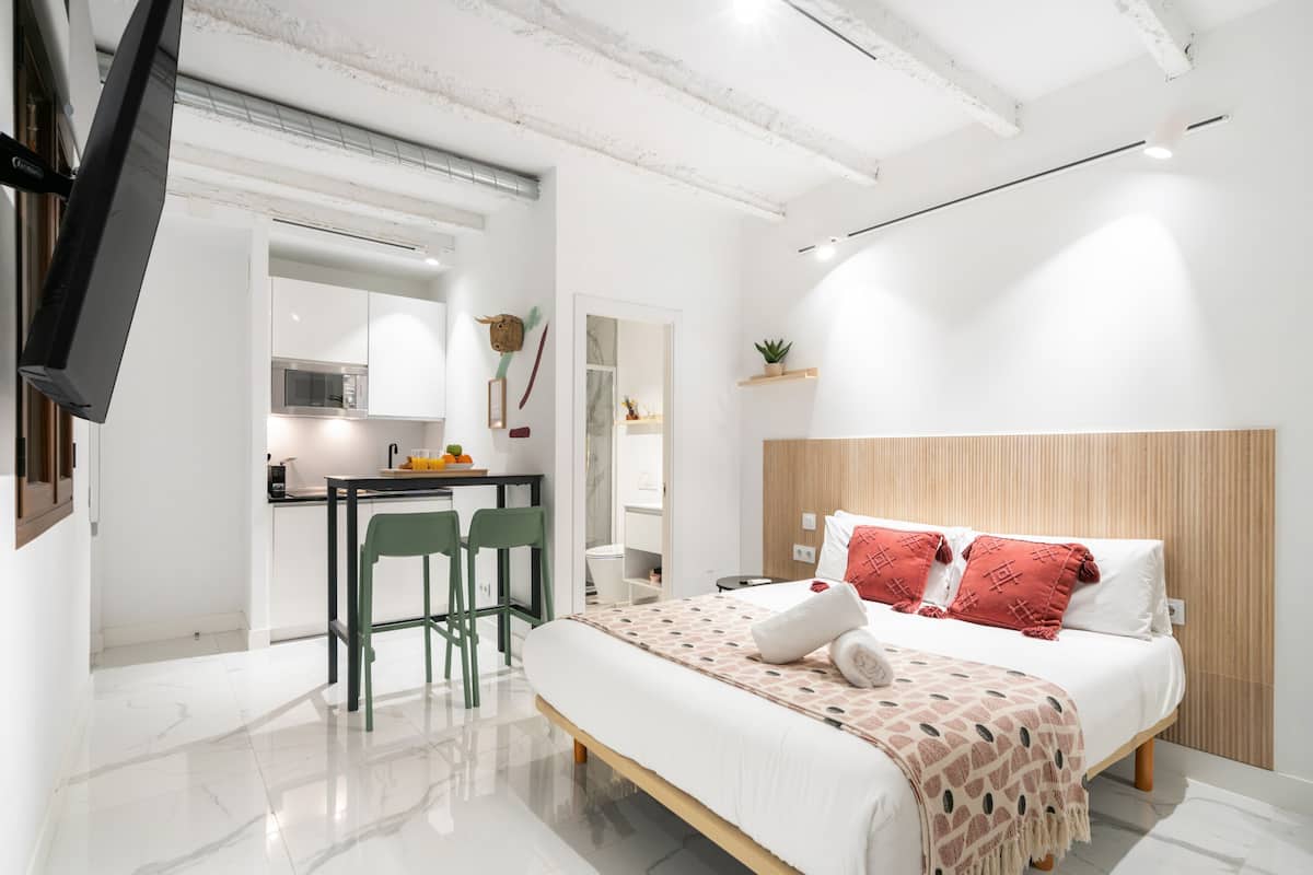 A modern hotel room with a bed, a desk, and a chair.