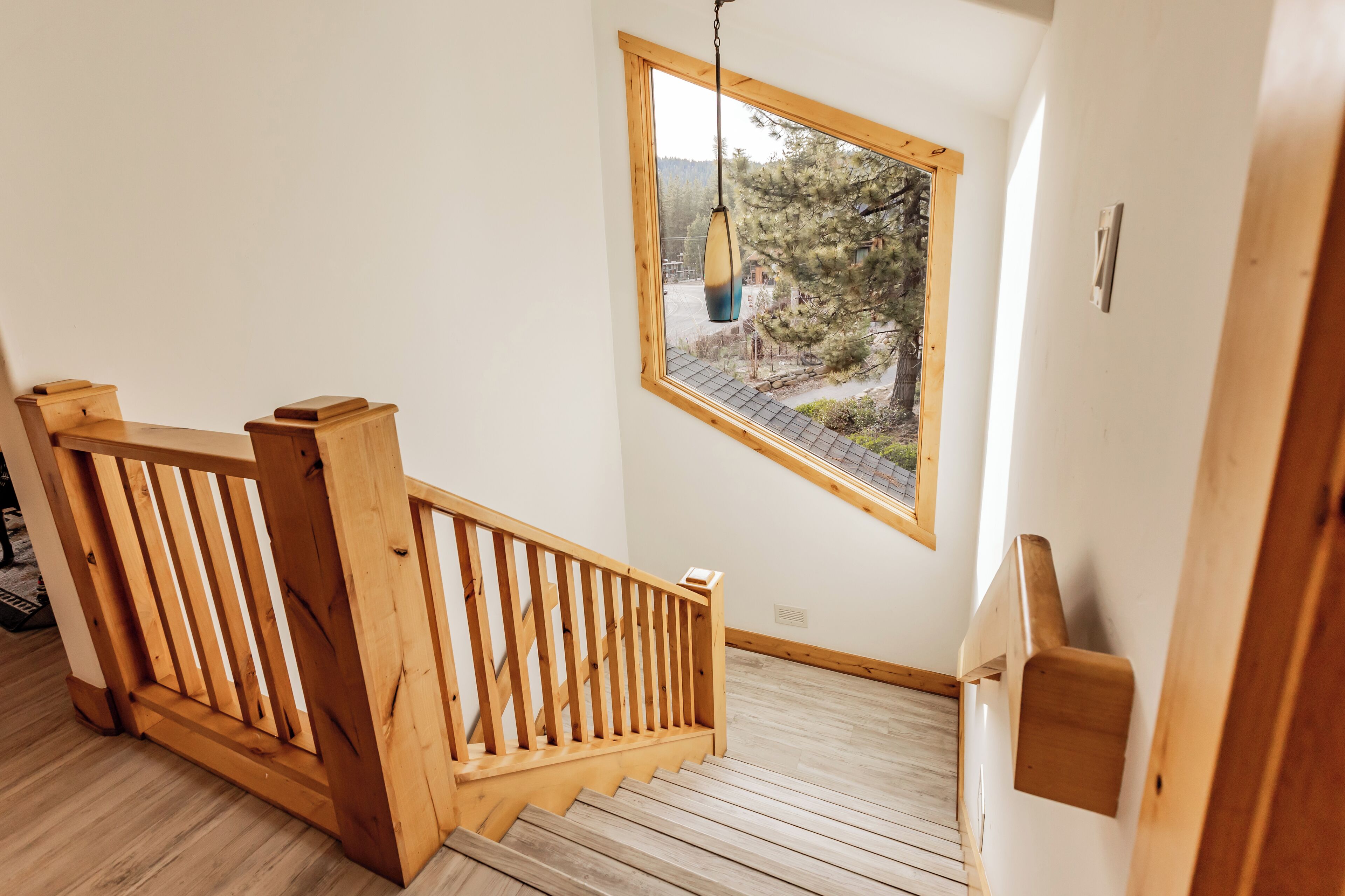 Una escalera de madera con vistas a un bosque a través de una ventana.