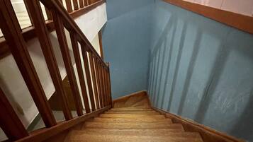 A wooden staircase with a handrail, leading to a landing with a blue wall and a white ceiling.