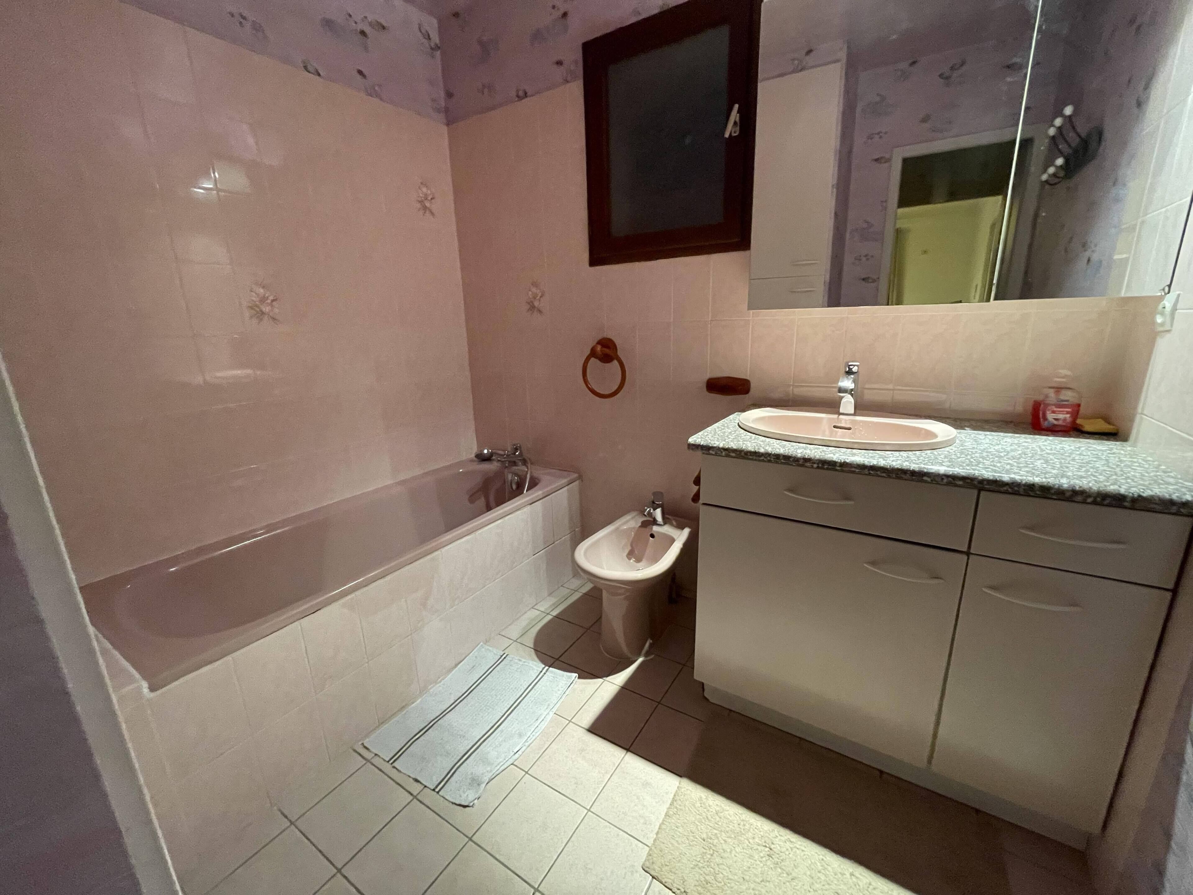 A bathroom with a bathtub, a sink, a bidet, and a mirror.
