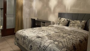 Een slaapkamer met een bed, een bureau en een stoel.