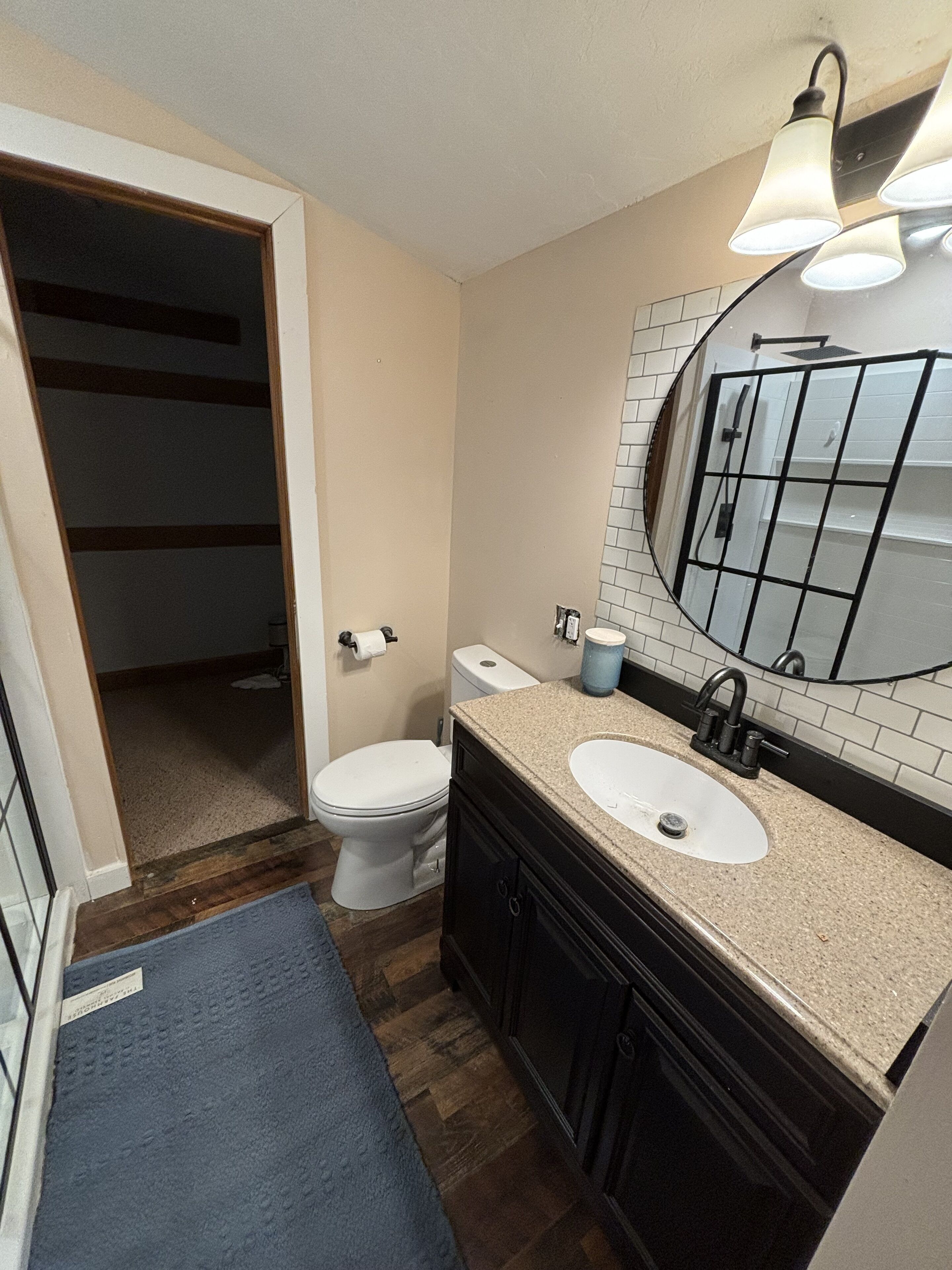 A bathroom with a toilet, sink, mirror, and a shower area.