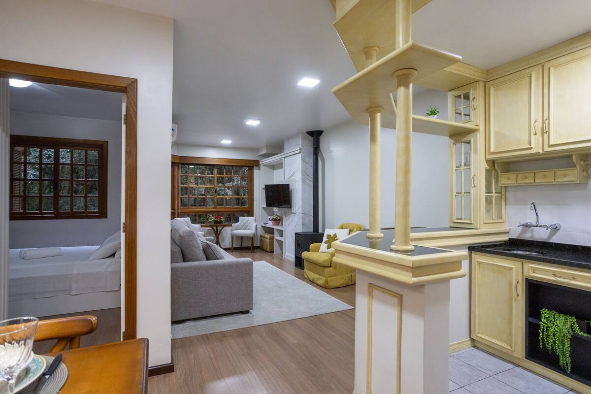 Una sala de estar moderna con sofá, mesa de comedor y área de cocina con armarios y estufa.
