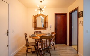 A dining room with a wooden table, chairs, a chandelier, a mirror, and a door. - LOCAR-IN GRAMADO- San Pietro (Gramado)