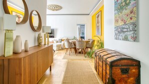 Un salon moderne avec une console en bois, un coin repas comprenant une table ronde et des chaises, et un grand coffre en bois.