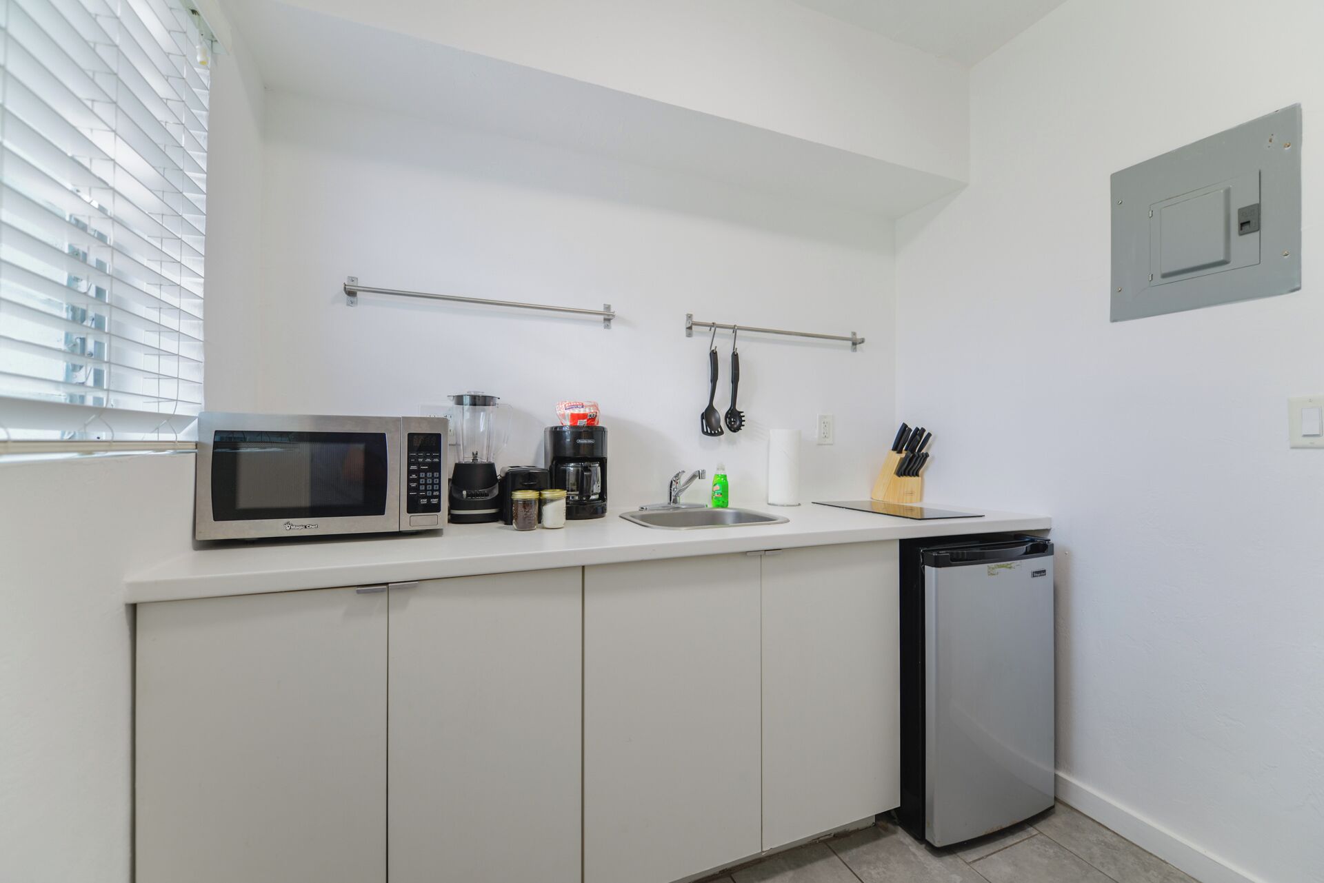 Eine kompakte Küchenzeile mit Mikrowelle, Mixer, Kaffeemaschine und Geschirrspüler.
