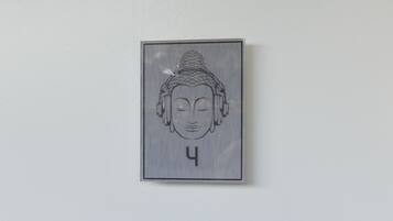 A wall-mounted artwork of a Buddha head with a serene expression, framed in a simple rectangular border.