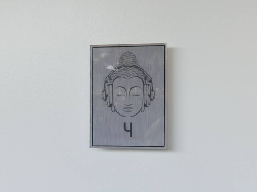 A wall-mounted artwork of a Buddha head with a serene expression, framed in a simple rectangular border.