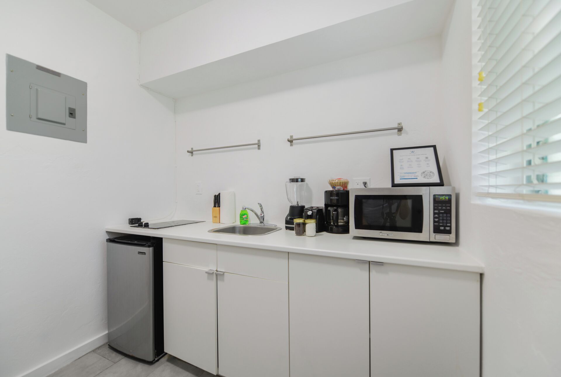 Une petite cuisine équipée d’un four à micro-ondes, d’une machine à café et d’un petit évier.