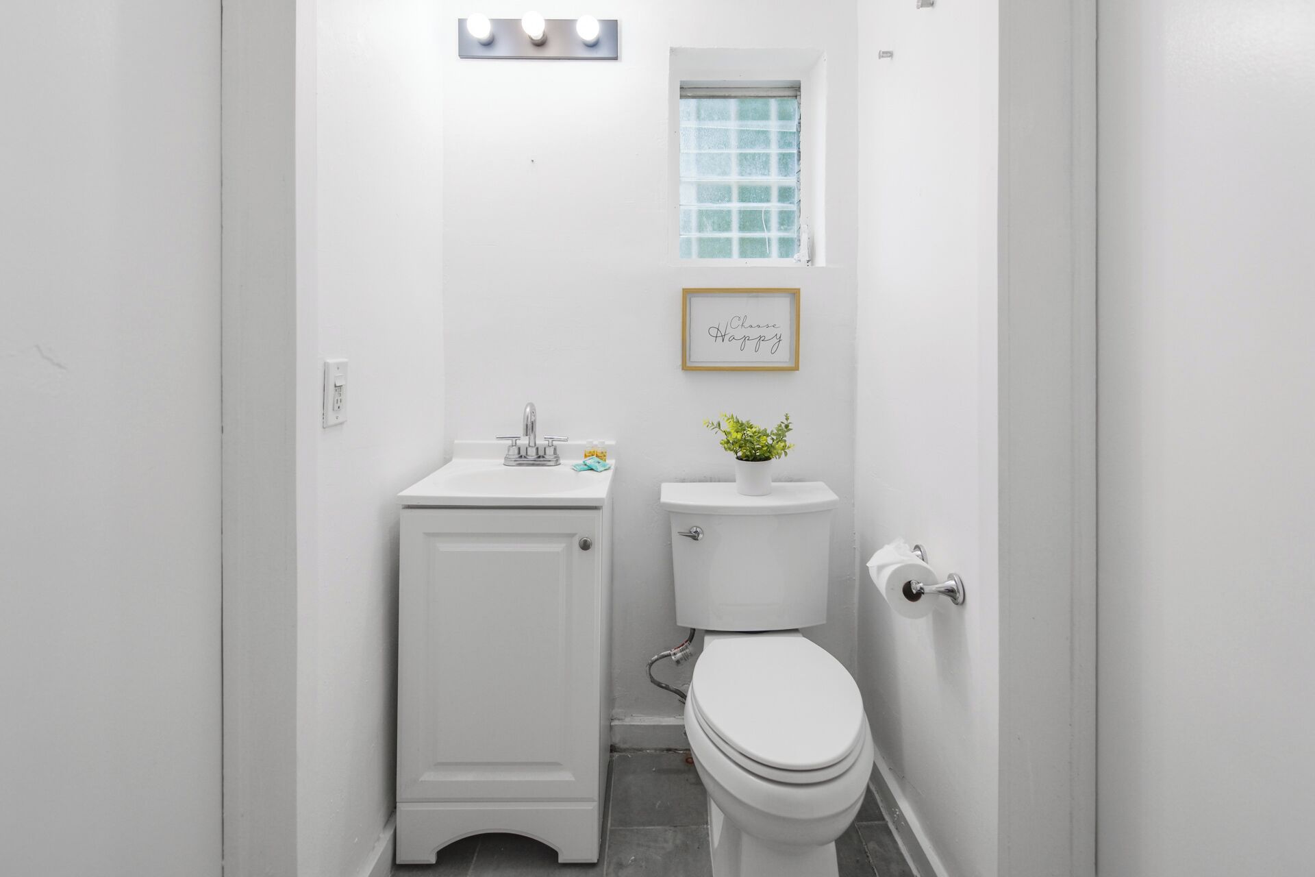 A compact bathroom with a white sink, a toilet, and a small window.