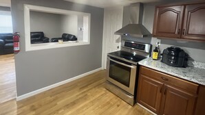 A kitchen with grey walls, wooden cabinets, a stainless steel oven, and a built-in microwave. - The Shack- 3 bedroom finished house (Leadwood)