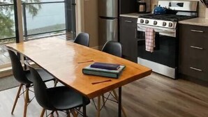 Een moderne keuken met een eettafel, stoelen, een koelkast, fornuis en kasten.