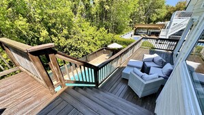 Une terrasse en bois avec un escalier menant à un espace de détente couvert, agrémenté de coussins.