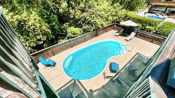 Relax by the oval-shaped pool surrounded by a deck and lush greenery.