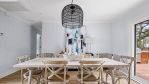 A dining area with a white table and six chairs, a black hanging light fixture, and a large abstract painting on the wall. - Old Village - 3 BR with Private Backyard & Deck (Mount Pleasant)