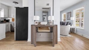 A modern kitchen with a black refrigerator, a mirrored console table with two lamps, and a grey armchair by a window. - Old Village - 3 BR with Private Backyard & Deck (Mount Pleasant)