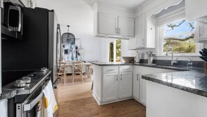 A modern kitchen with white cabinetry, a black refrigerator, and a granite countertop. - Old Village - 3 BR with Private Backyard & Deck (Mount Pleasant)
