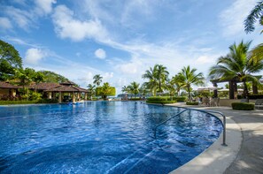 A large outdoor swimming pool with clear blue water, surrounded by palm trees and lounge chairs. - Delmar Bay Residence Los Suenos Resort (Herradura)