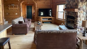 A log cabin interior with a fireplace, television, and wooden furniture. - Stunning Lake Petenwell Log Home Near Sand Valley Golf (Rome)
