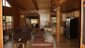 A log cabin interior with a living room, dining area, and kitchen. - Stunning Lake Petenwell Log Home Near Sand Valley Golf (Rome)
