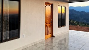 A corridor with large windows and a door, leading to a terrace with a mountain view. - A single-family home w/ a serene view. Nonsmoking and pet-friendly environment. (Perez Zeledon)