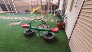 A children's play area with a seesaw, a slide, and artificial turf. - Charming 2-bedroom villa with Swimming pool, WiFi and AC in enchanting Shahrakan (Shahrakan)