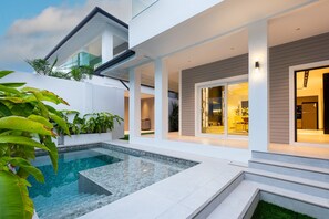 A modern house with a swimming pool, outdoor seating, and a well-lit interior. - New 2024 - Two Villa Compound - 9BR - Two Pools (Pattaya City)