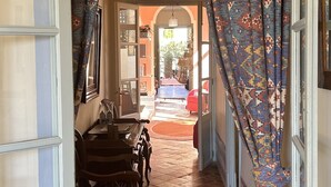An arched doorway leading to a room with patterned curtains, a tiled floor, and a red chair.