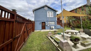 A blue house with a wooden fence, a patio with outdoor furniture, and a yellow shade sail. - Charming Studio in the Heart of Springfield (Jacksonville)