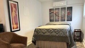A bedroom with a bed, a chair, and artwork on the walls. - Charming Studio in the Heart of Springfield (Jacksonville)