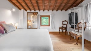 A bedroom with a large bed, a mirror, a window with a view of greenery, and a wooden ceiling. - Villa in Sinalunga with 1 bedrooms sleeps 4 (Sinalunga)