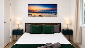Ein Schlafzimmer mit einem Bett, zwei Nachttischen, einem Gemälde und einem Fenster.
