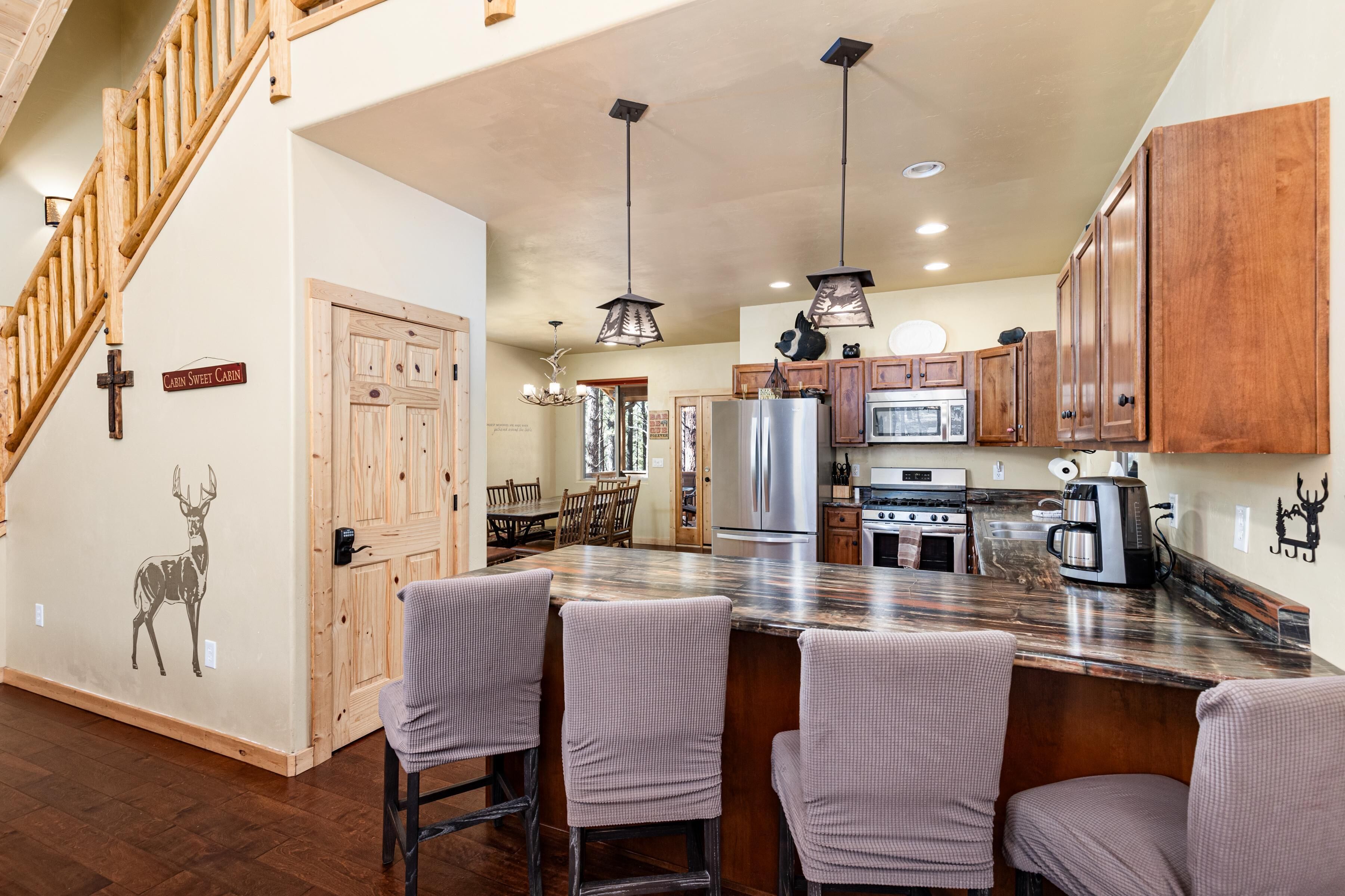 A spacious kitchen with wooden cabinets, a marble island with bar stools, and a cross on the wall.