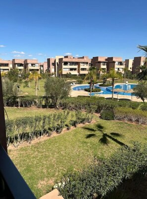 Un quartier résidentiel avec des immeubles d’appartements modernes, une piscine et des espaces verts bien entretenus.