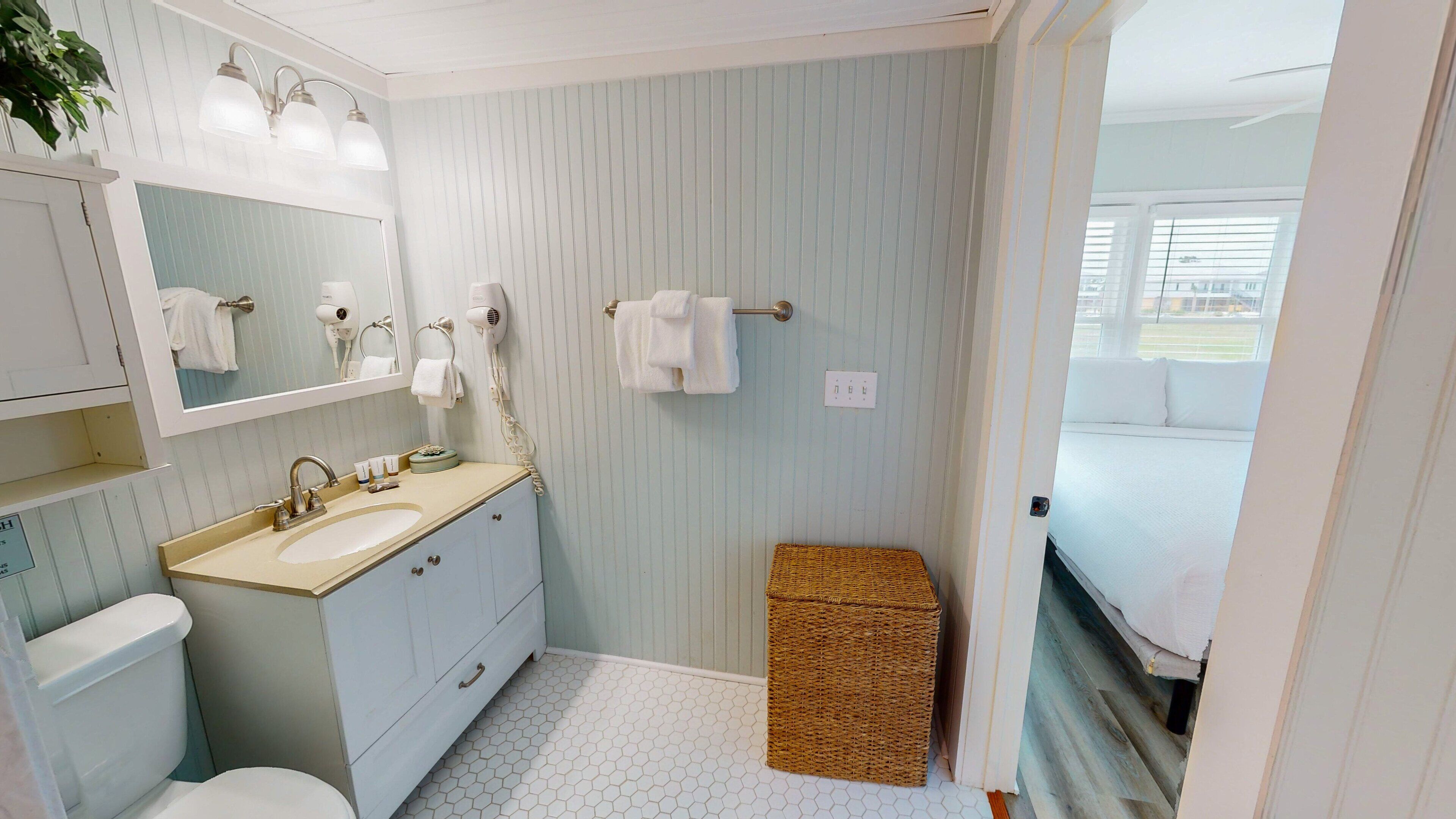 A bathroom with a sink, mirror, towel rack, and a wicker basket.
