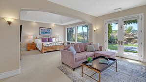 A spacious living room with a large window, a sofa, a coffee table, and a bed with a view of the garden. - Hilltop Del Mar Lux Infinity Pool Panoramic Views (San Diego)