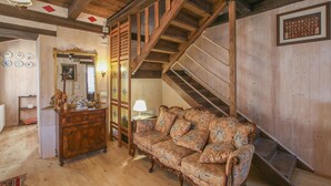 Een houten interieur met een bank, een dressoir, een spiegel en een trap.