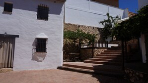 A white building with a stone wall, a staircase, and a table with chairs. - Tranquilidad Rural. Molino Viejo de Salar (Salar)