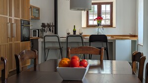 A compact kitchen with a dining table, chairs, and a bowl of fruit. - Tranquilidad Rural. Molino Viejo de Salar (Salar)
