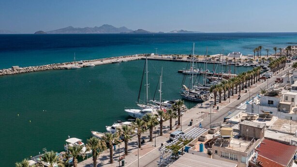 A marina with boats docked, a pier, and a coastal town with buildings and palm trees. - Casa Lemonia - 110 sqm Maisonette (Kardamaina)