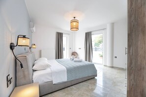 A modern bedroom with a bed, bedside lamps, a radiator, and a view to the outside. - La Bella Kos Center with Terrace Near Beach (Kos)