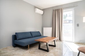 A modern living room with a sofa, a small wooden table, and a radiator. - La Bella Kos Center with Terrace Near Beach (Kos)