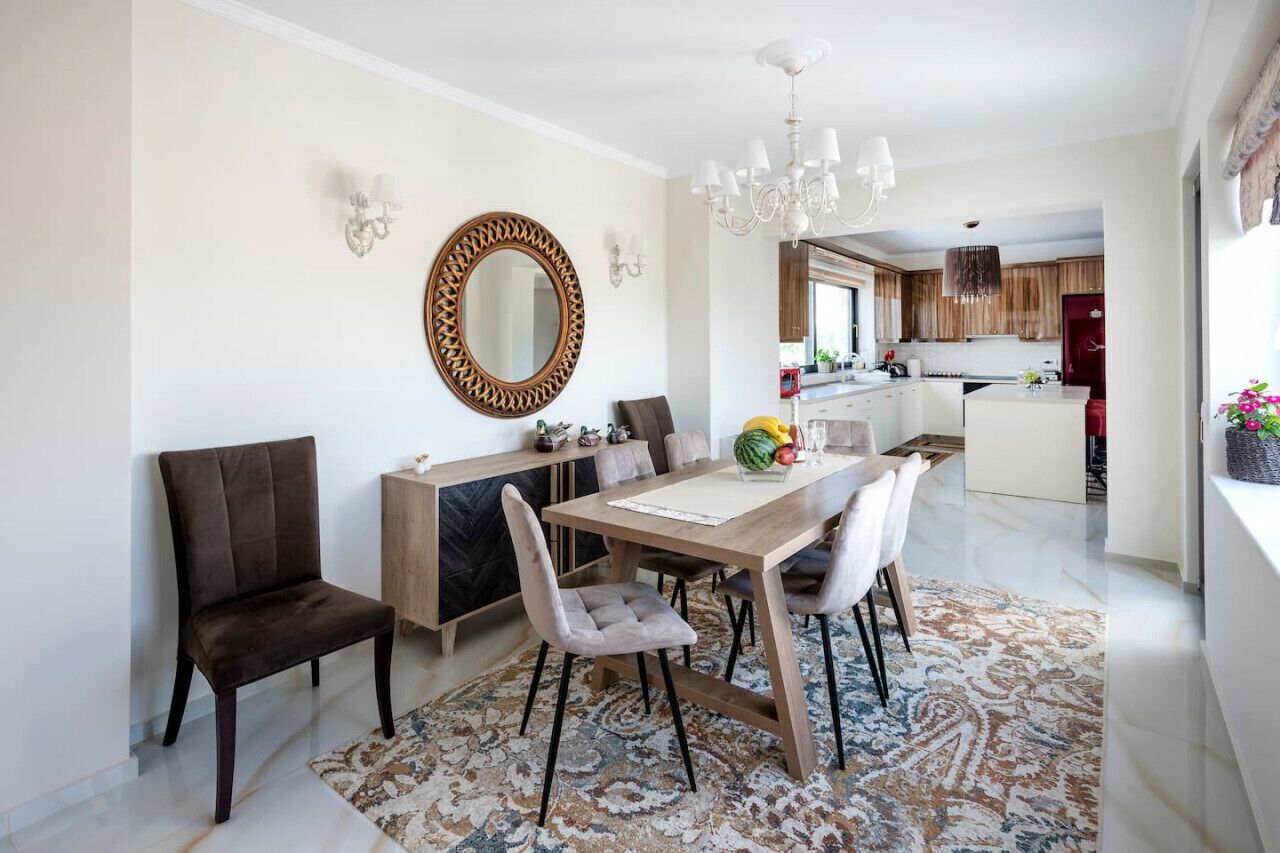 Un espace repas moderne avec une table en bois, des chaises rembourrées et un tapis à motifs.