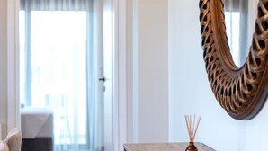 Een hotelkamer met een grote spiegel, een nachtkastje met een lamp, en uitzicht op de gang.